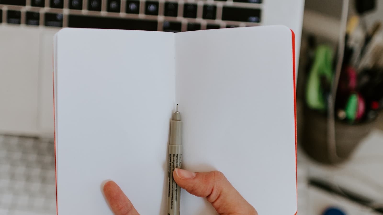 Persona escribiendo en un cuaderno sobre un escritorio mientras planea la estrategia de marca de una PyME