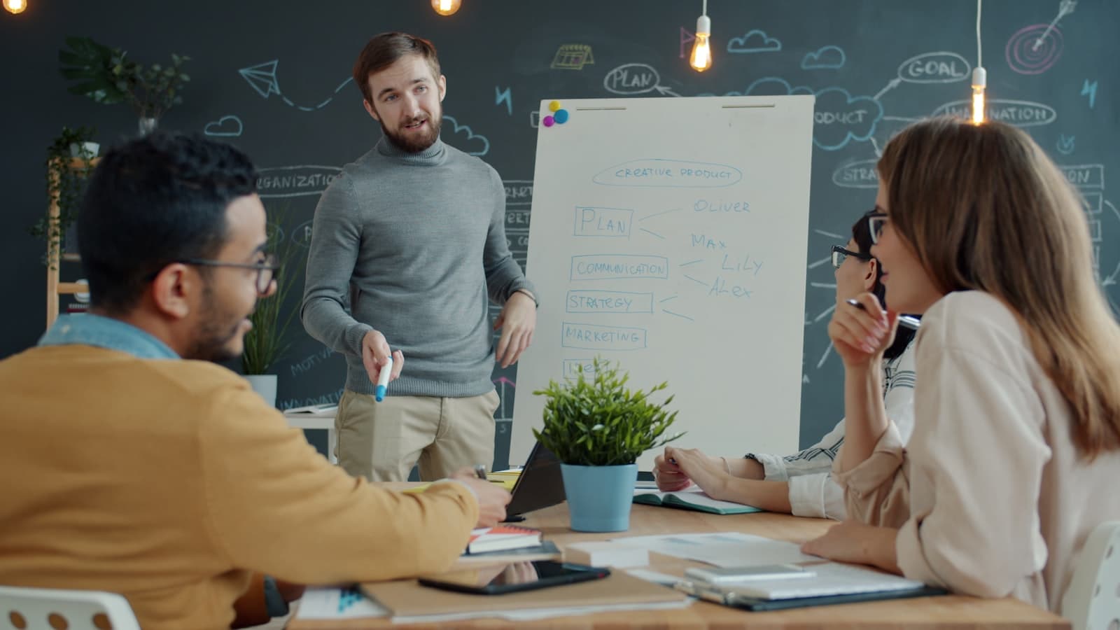 Equipo de consultoría revisando una estrategia de marketing digital frente a un pizarrón en una oficina creativa