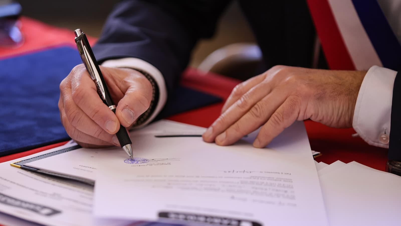 Persona firmando con pluma un documento legal sobre un escritorio, como al registrar una marca ante el IMPI