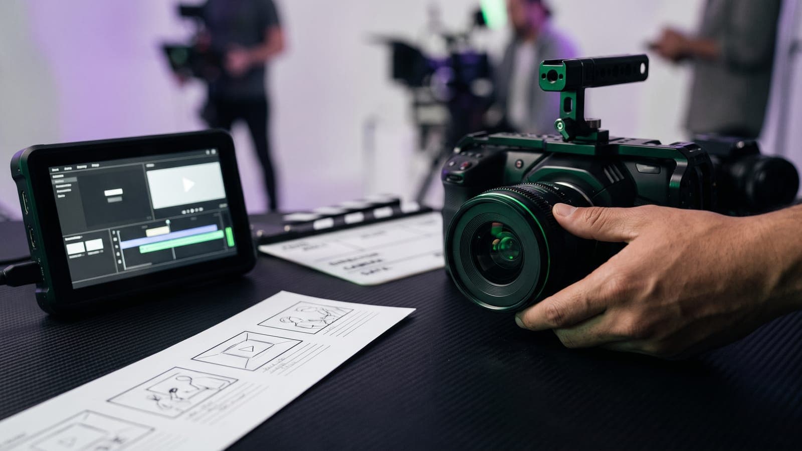 Mano sosteniendo una cámara de cine en un set con crew al fondo, junto a storyboard, claqueta y monitor con timeline de edición: la producción detrás de cuánto cuesta un video corporativo en México