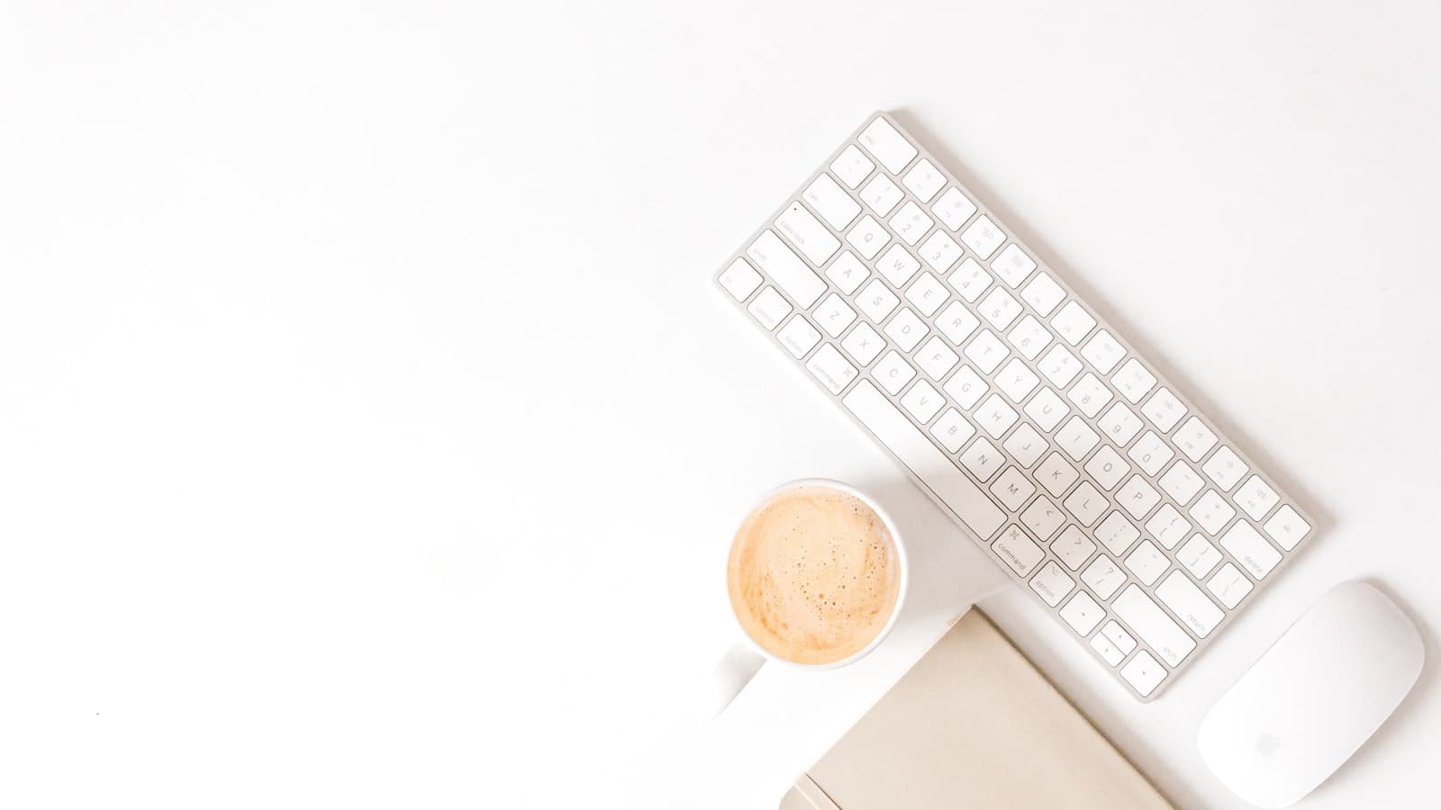 Escritorio minimalista con cuaderno, teclado y café para planear y construir tu marca personal paso a paso