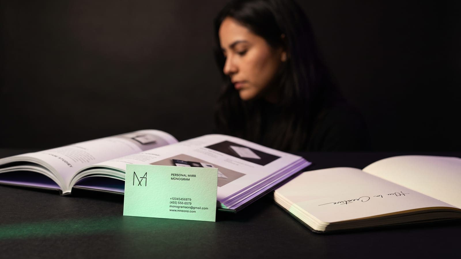 Tarjeta de presentación con monograma personal frente a un portafolio impreso y cuaderno con firma: el kit para crear una marca personal