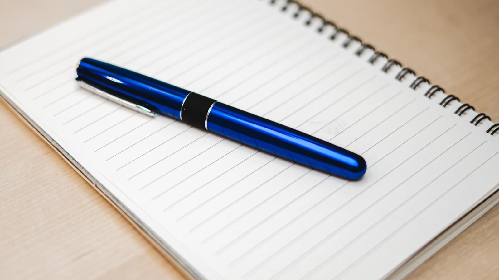 Pluma sobre un cuaderno abierto en un escritorio, listo para planear y distribuir el presupuesto de marketing