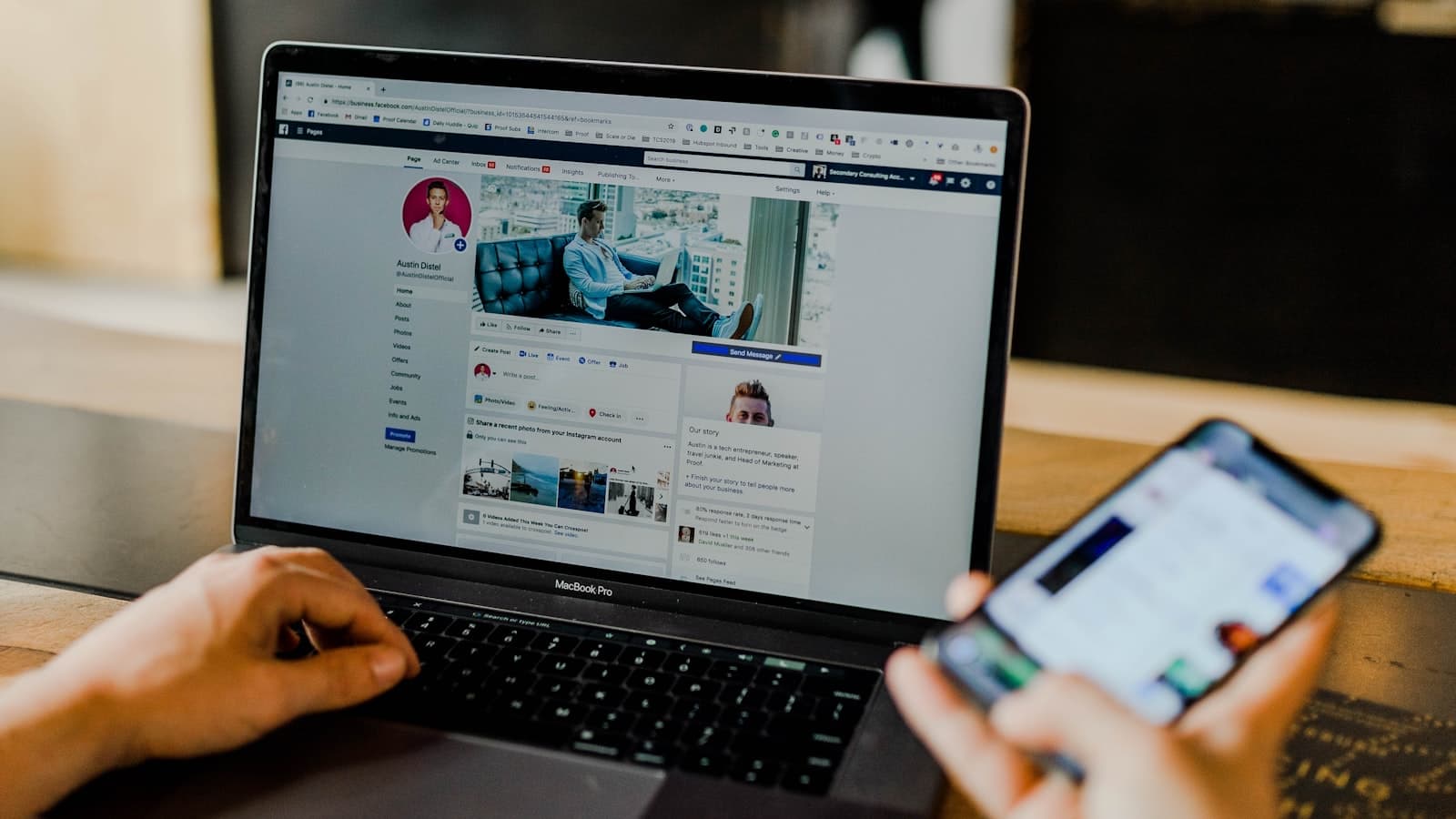 Persona usando laptop y celular para gestionar las redes sociales de su negocio desde el escritorio